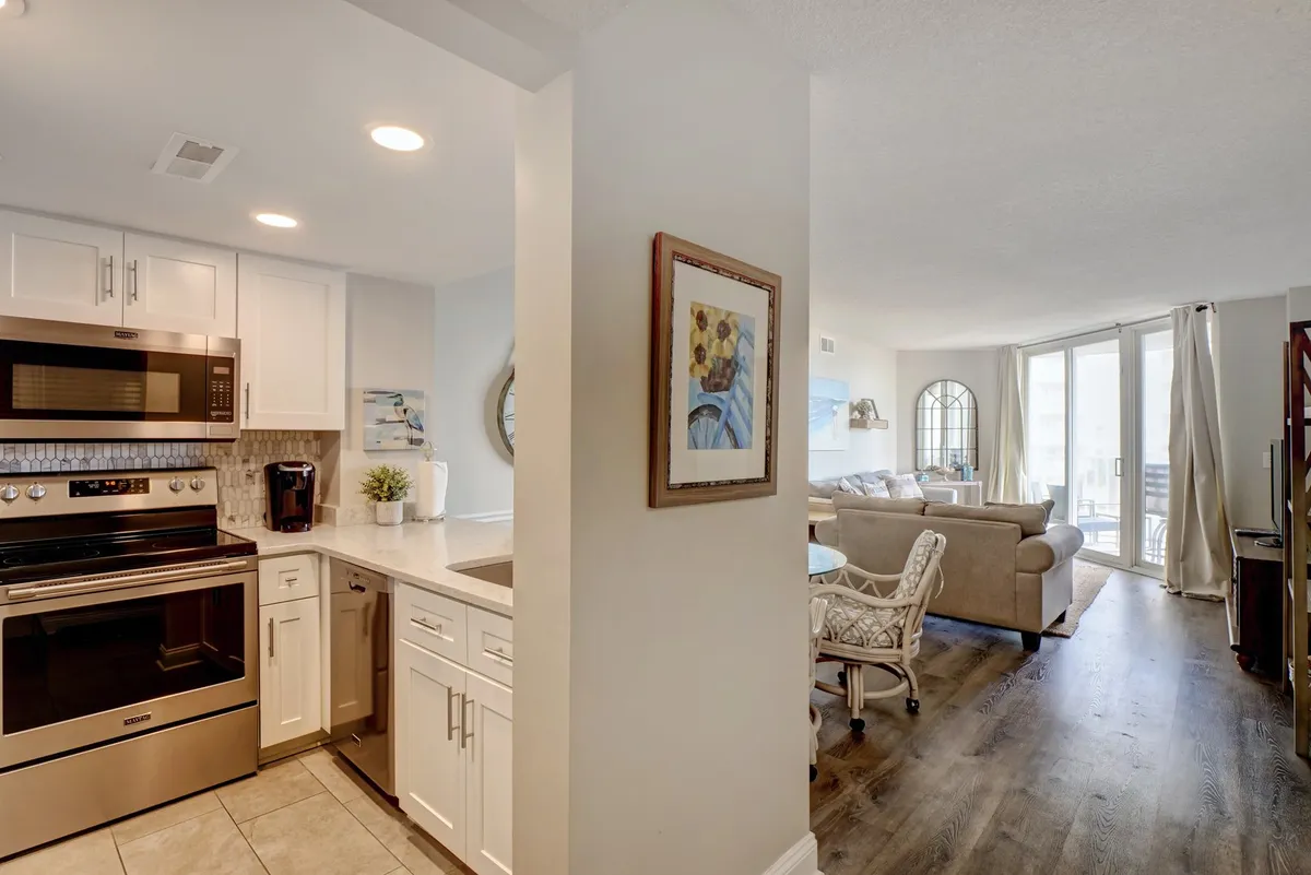 A welcoming open-plan interior that seamlessly blends the kitchen, dining area, and living room. The image features modern kitchen appliances, a spacious countertop, a stylish dining table with chairs, and comfortable living room seating, all bathed in natural light.