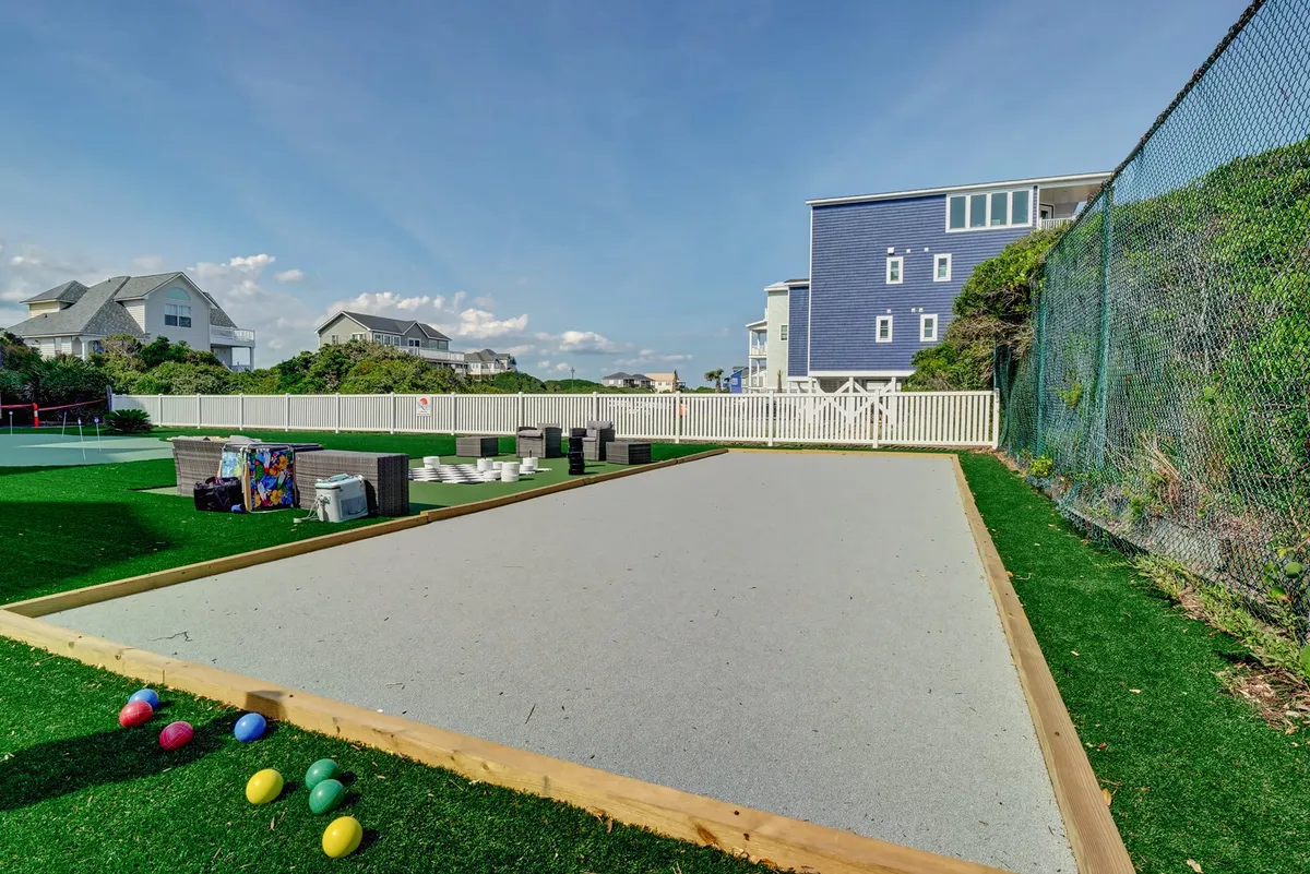 An inviting bocce court with colorful bocce balls set amidst green landscaping and nearby houses. The space encourages playful interaction and group games in a relaxed, cheerful environment.