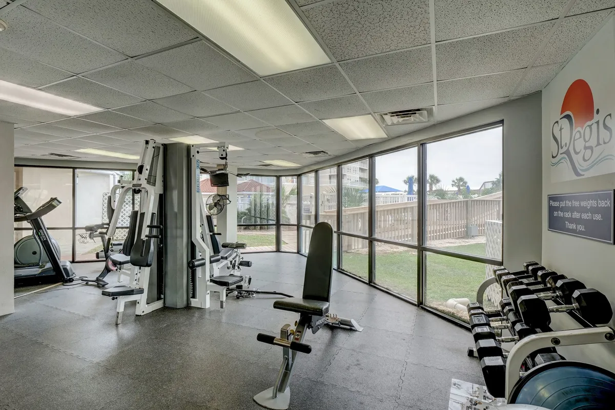 A bright, spacious fitness center with a variety of exercise equipment, large windows offering natural light, and motivational signage. The area encourages an energetic atmosphere for guests wanting to recharge after a work session.